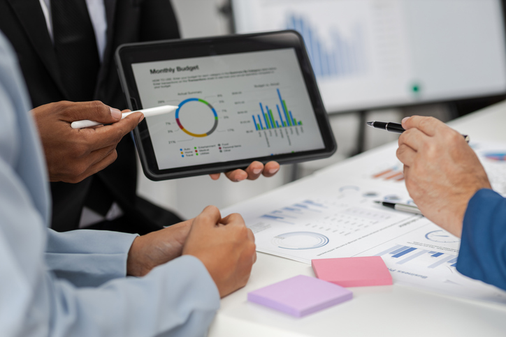 Business consultant meeting is analyzing market situation by financial chart and planning business investment strategy on tablet.